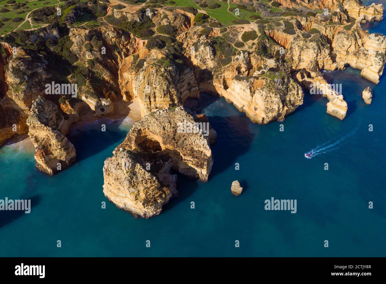 Portugal, Algarve, Lagos, Drone vue du bateau à moteur se déplaçant vers les piles de mer de Ponta da Piedade promontoire Banque D'Images