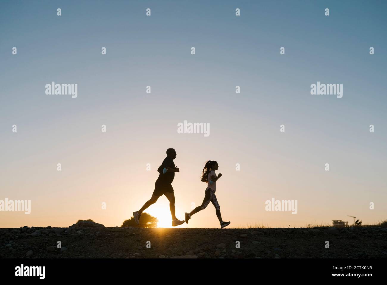 Silhouette de l'athlète et de la femme qui s'élancé contre un ciel dégagé pendant coucher de soleil Banque D'Images