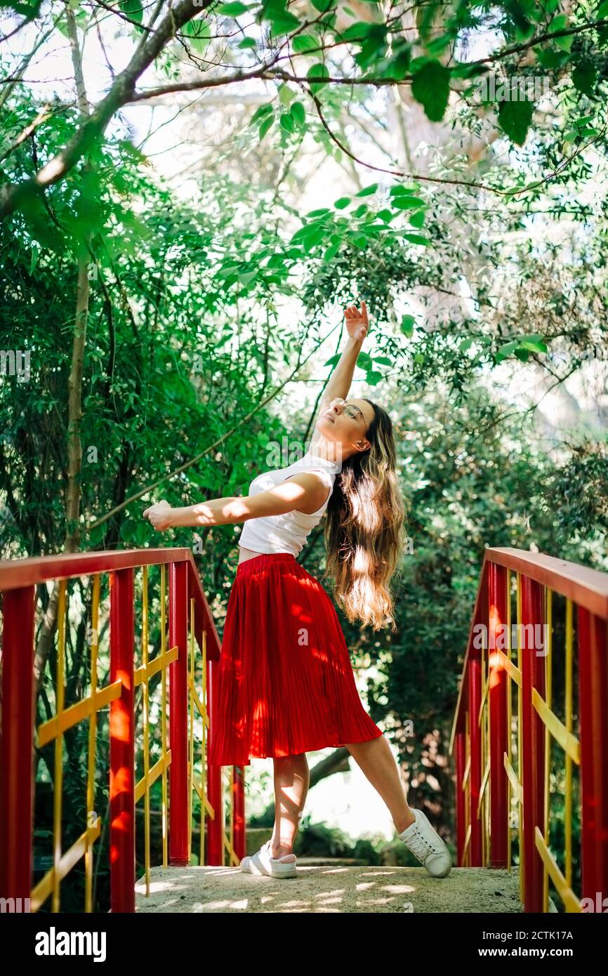 Jeune femme pratiquant le ballet sur la passerelle contre les arbres dans le parc Banque D'Images