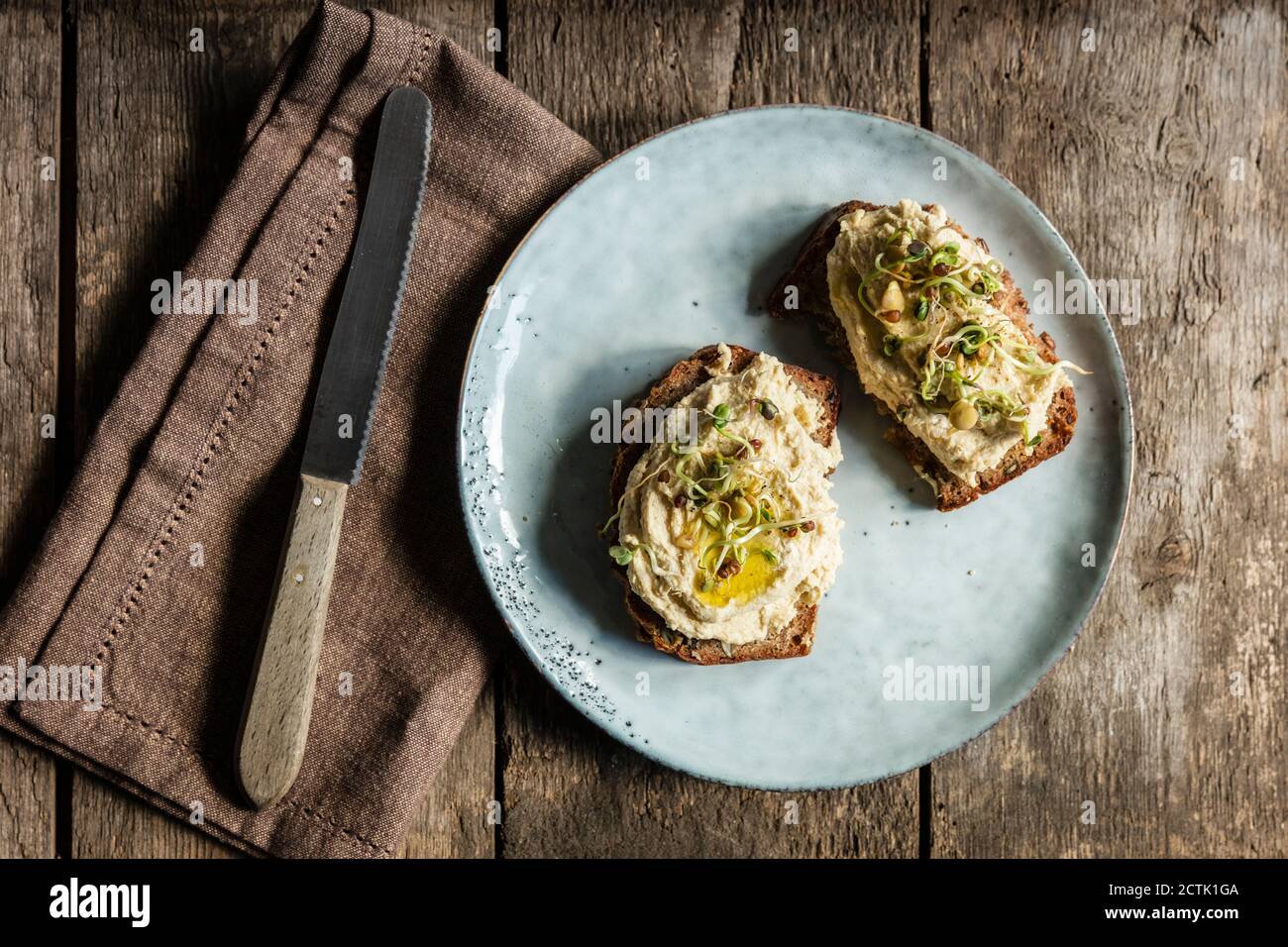 Couteau de table et tranches de pain avec houmous et pousses Banque D'Images