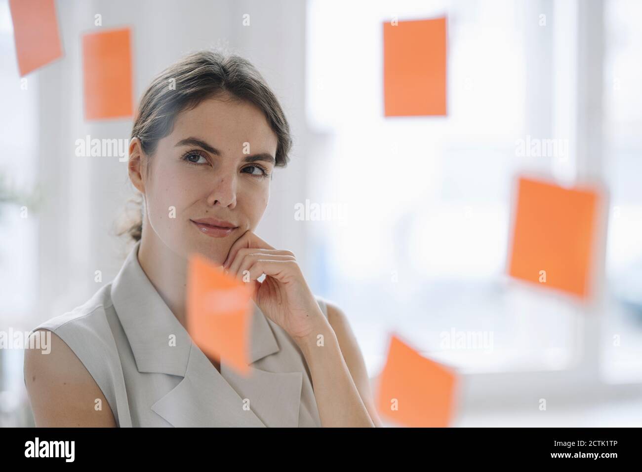 Femme d'affaires brainstorming en se tenant près du mur de verre au bureau Banque D'Images