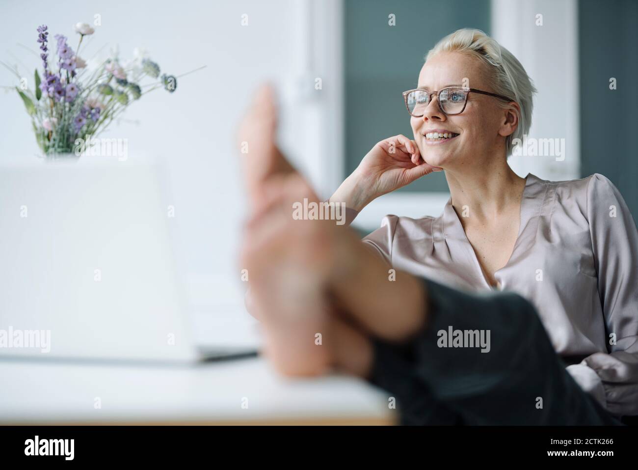 Femme d'affaires attentionnés avec ses pieds sur le bureau pour se détendre au bureau Banque D'Images