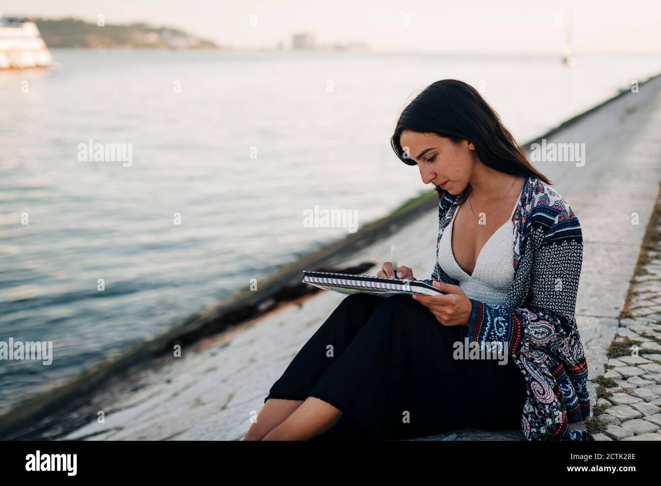 Une jeune femme paintant assis au bord de la rivière Banque D'Images