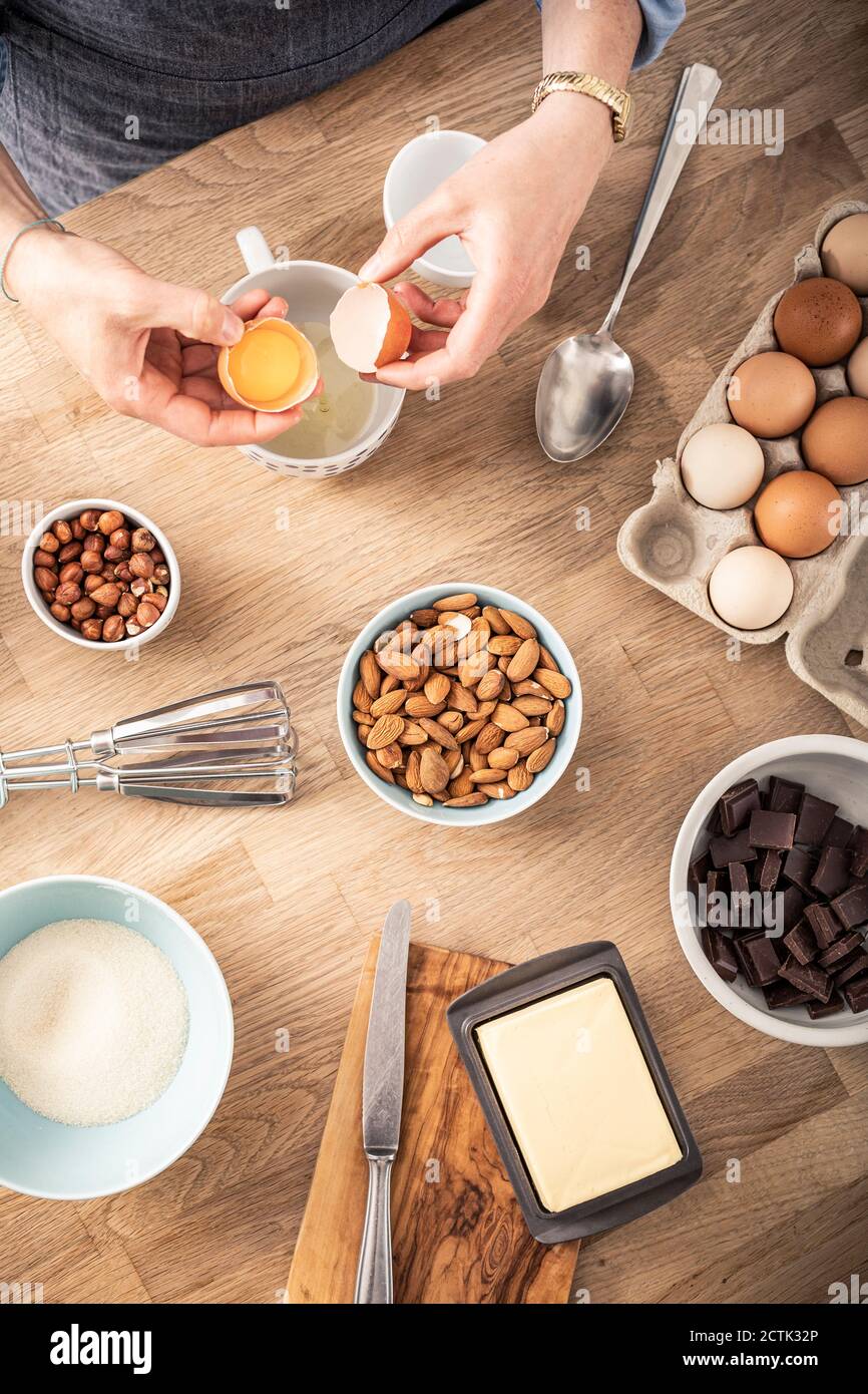 Femme séparant le blanc d'œuf et le jaune d'œuf tout en se tenant à îlot de cuisine Banque D'Images