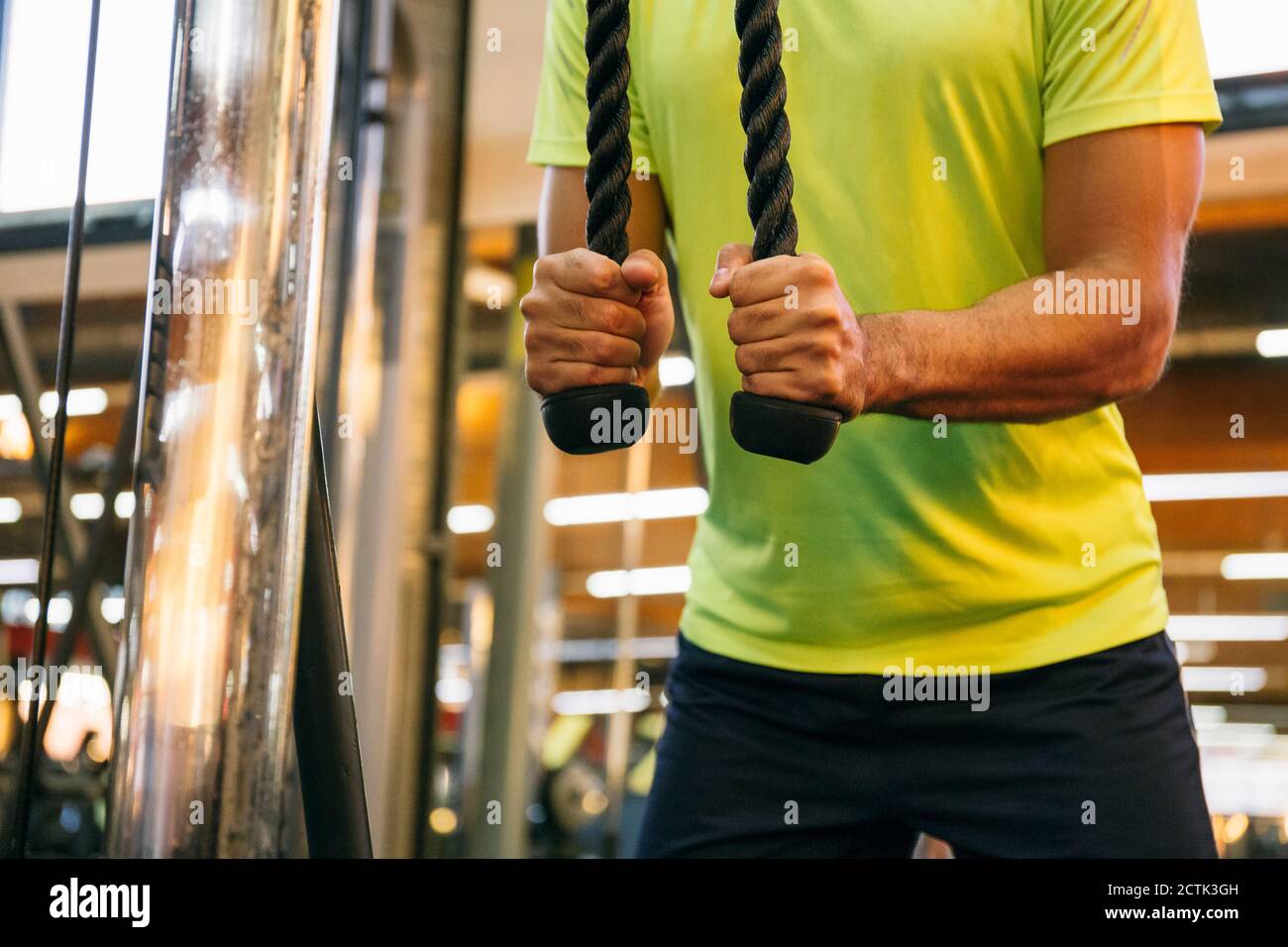 Gros plan de l'athlète masculin s'exerçant avec des cordes dans la salle de gym Banque D'Images