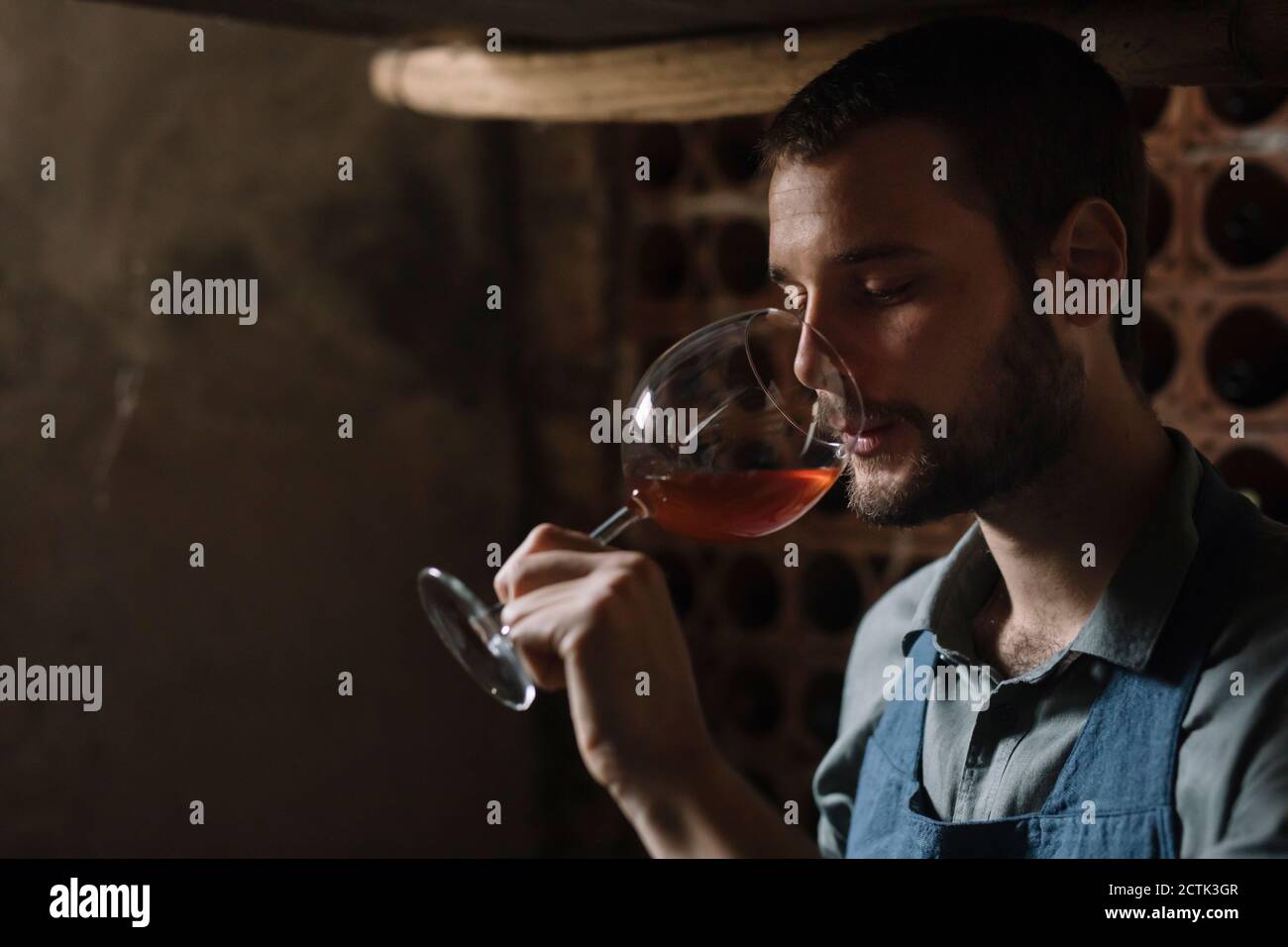 Jeune barbu qui boit du vin en verre à la cave Banque D'Images