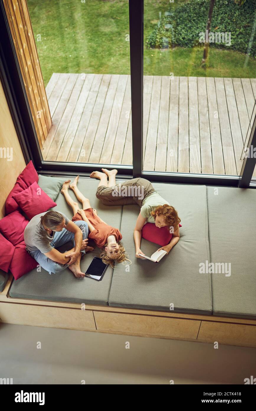 Fille couchée par des parents sur le lit à la maison Banque D'Images