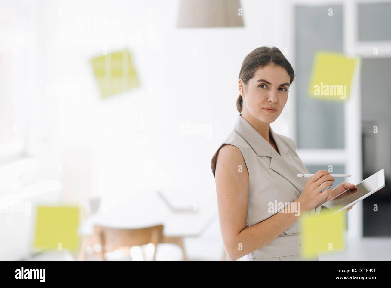 Une femme d'affaires remue-méninges lorsqu'elle utilise une tablette numérique au bureau Banque D'Images