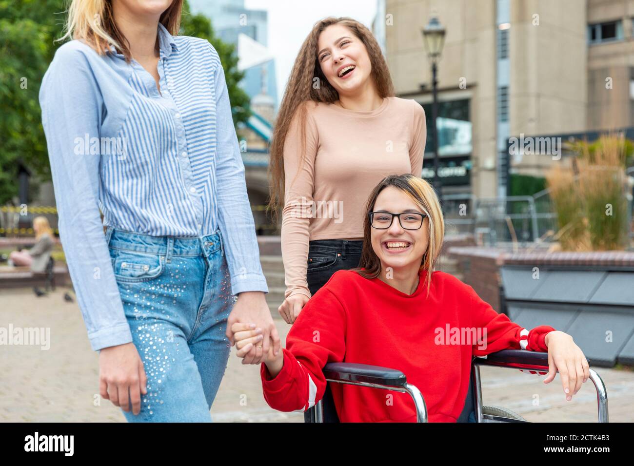 Bonne femme handicapée en fauteuil roulant, passant du temps libre avec une femme amis en ville Banque D'Images