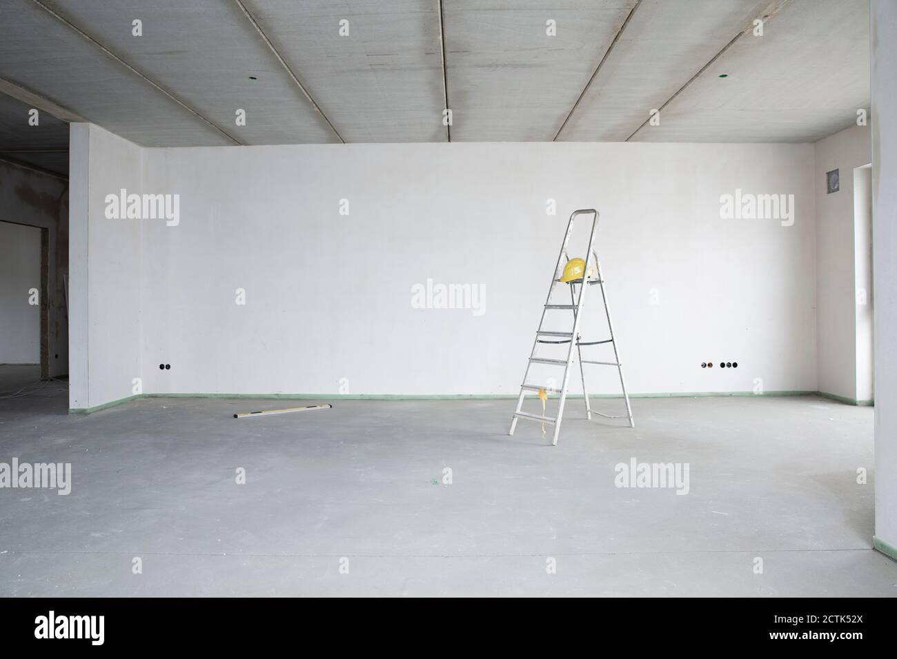 Échelle avec casque contre le mur dans la maison en rénovation Banque D'Images