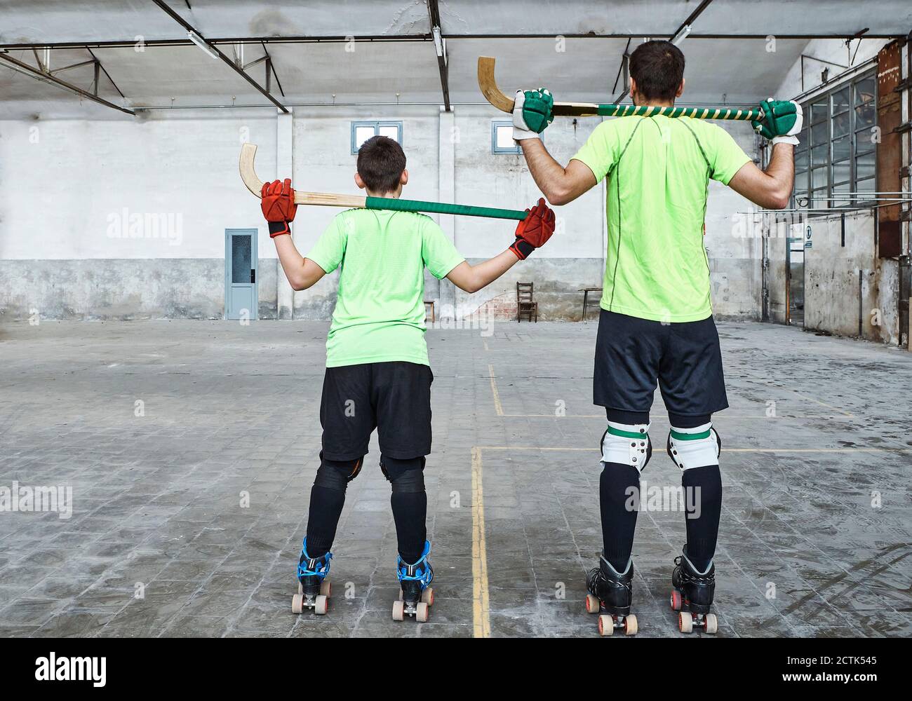 Père et fils en uniforme sportif tenant des bâtons de hockey à cour Banque D'Images