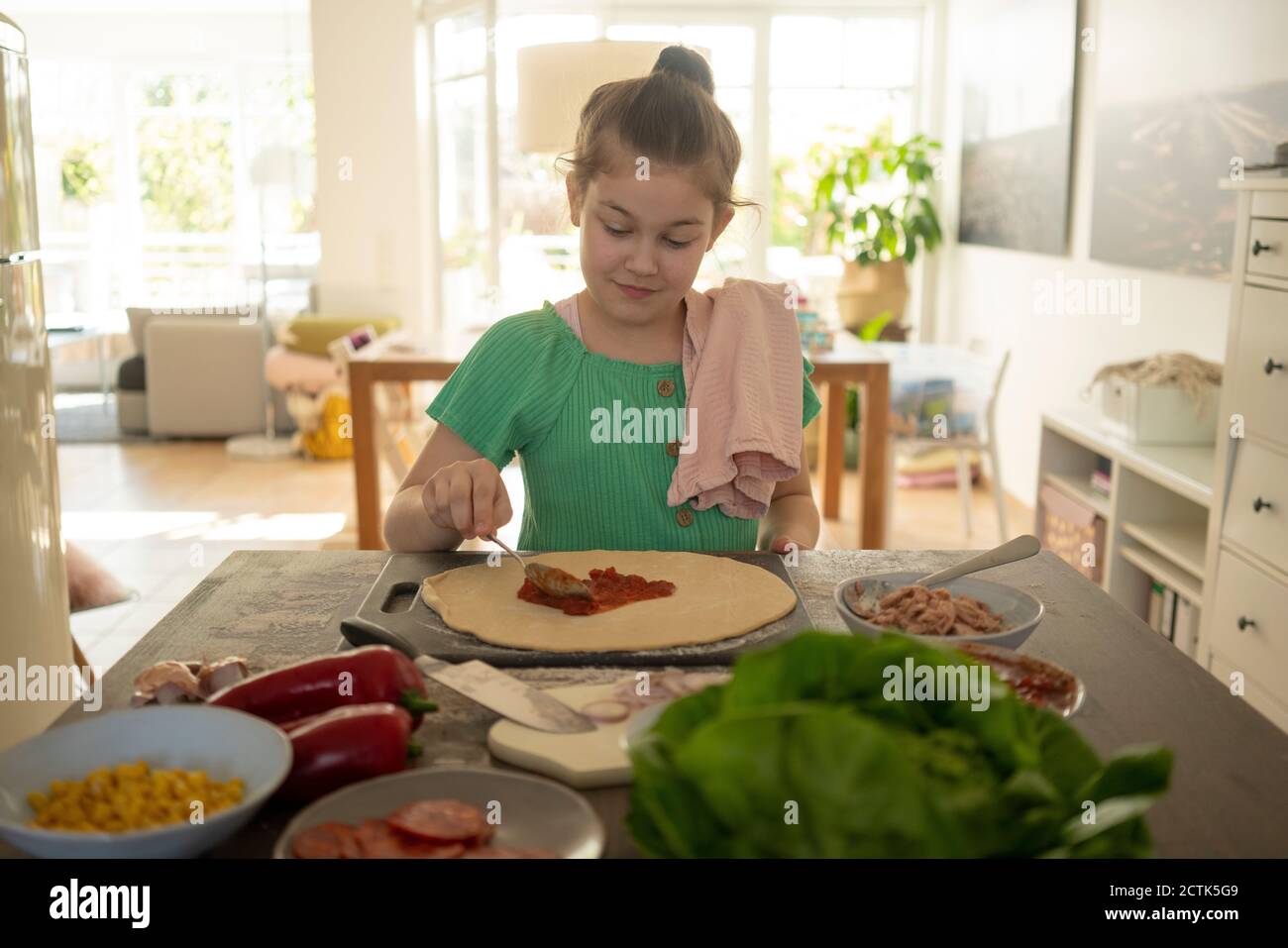 Jolie fille préparant une pizza sur une île de cuisine Banque D'Images