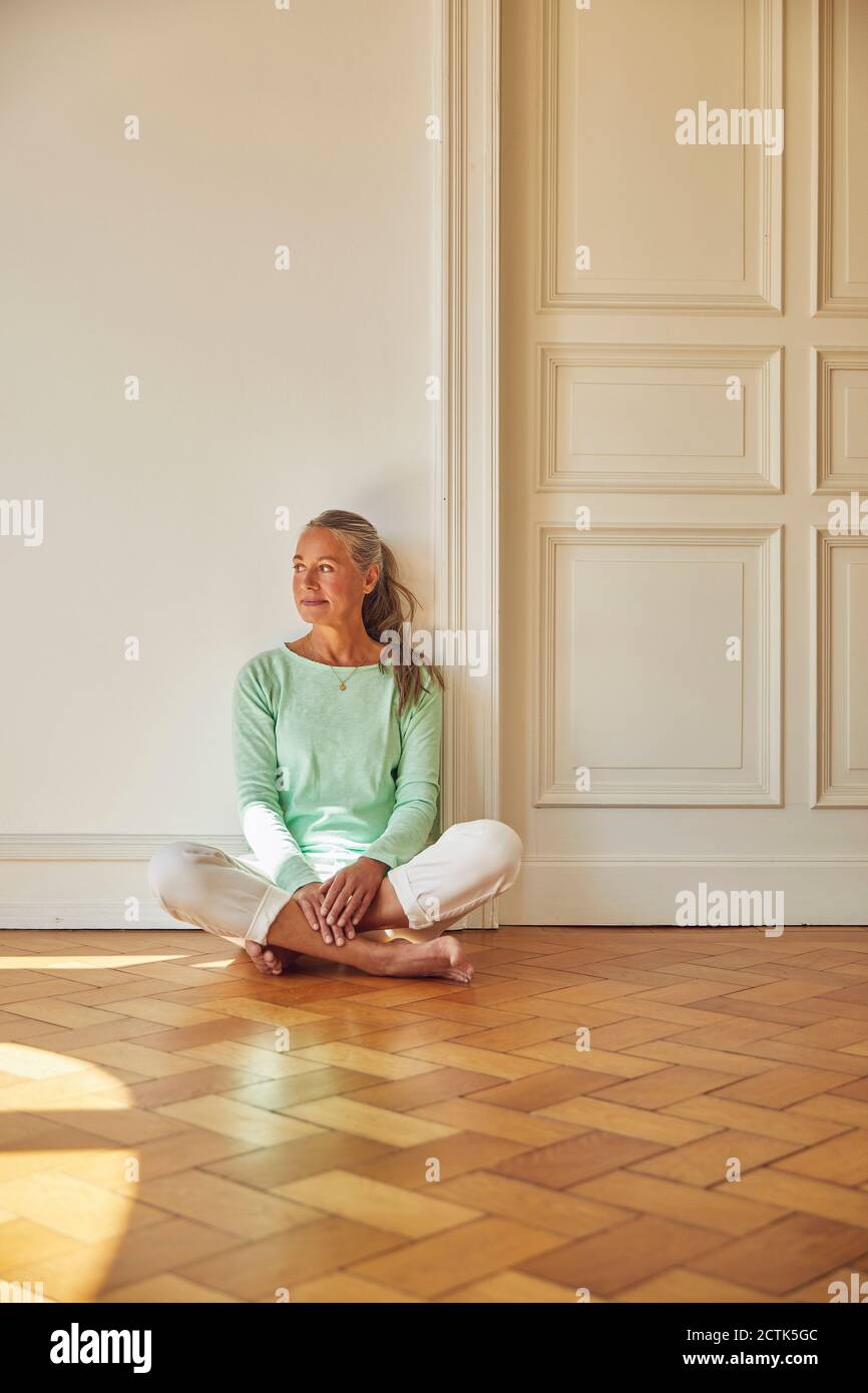 Femme attentionnés assise au sol à la porte à la maison Banque D'Images