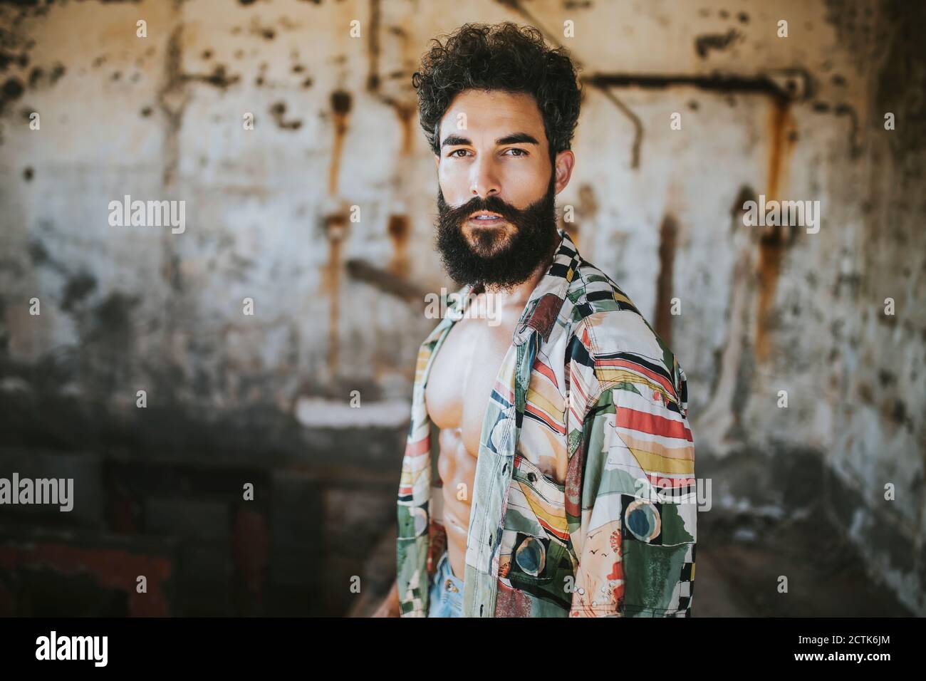 Homme barbu debout avec une chemise ouverte contre l'ancien mur Banque D'Images