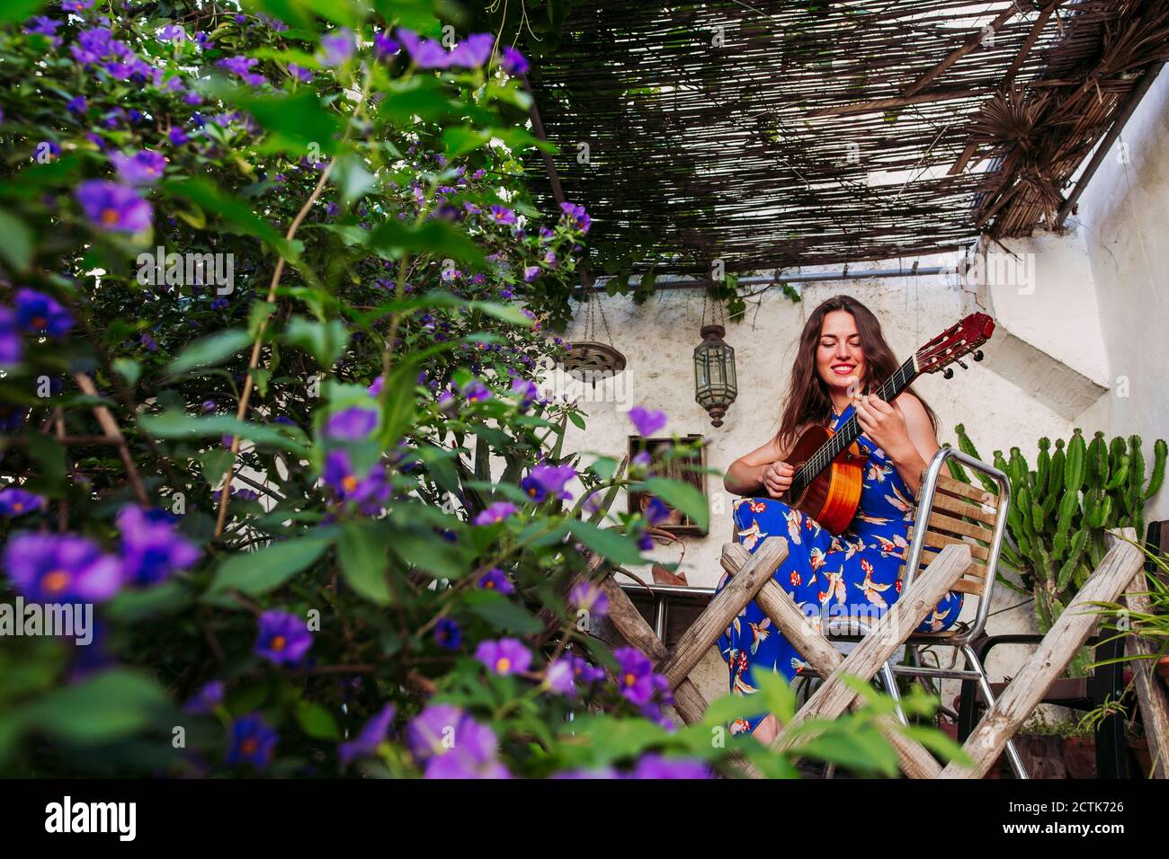 Femme souriante pratiquant la guitare sur le balcon Banque D'Images