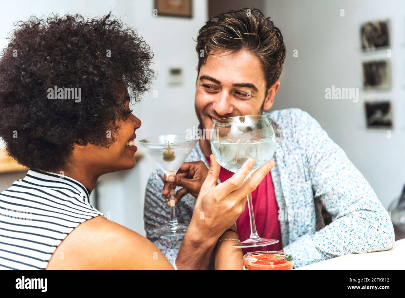 Gros plan d'un couple heureux se regardant les uns les autres pendant qu'il boit cocktails au bar Banque D'Images