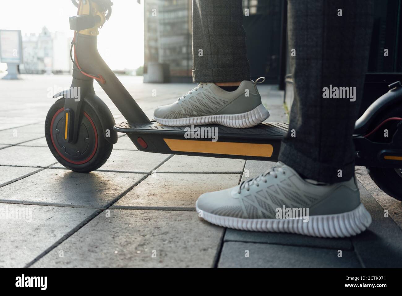 Section basse de l'entrepreneur masculin portant des chaussures de sport  pendant la conduite scooter électrique au centre-ville Photo Stock - Alamy
