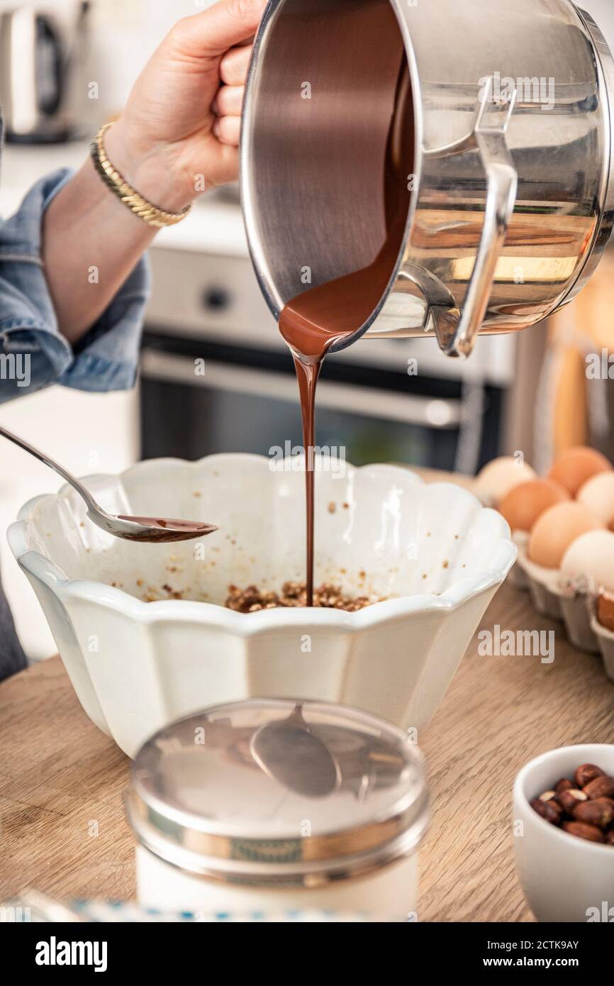 Femme versant du chocolat fondu à la main dans un bol de cuisine Banque D'Images