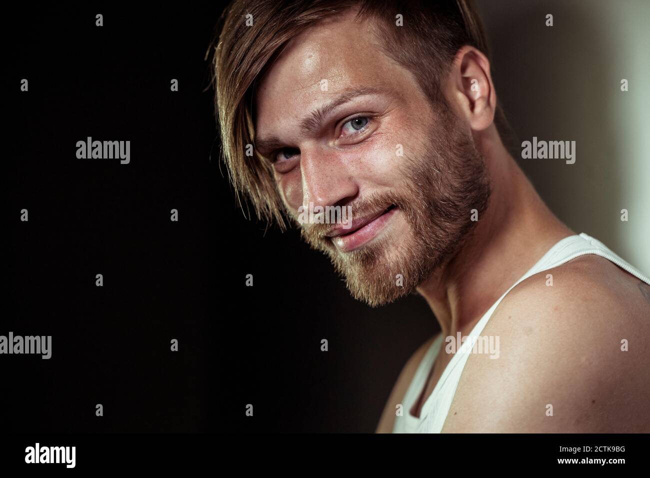 Gros plan sur un beau homme barbu souriant contre le mur Banque D'Images