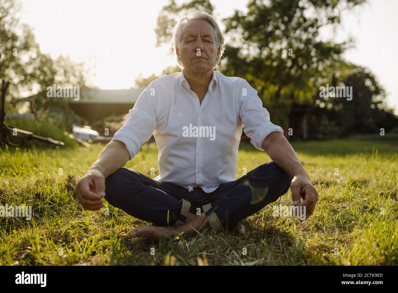 Homme pratiquant le yoga en étant assis en position lotus à la cour Banque D'Images