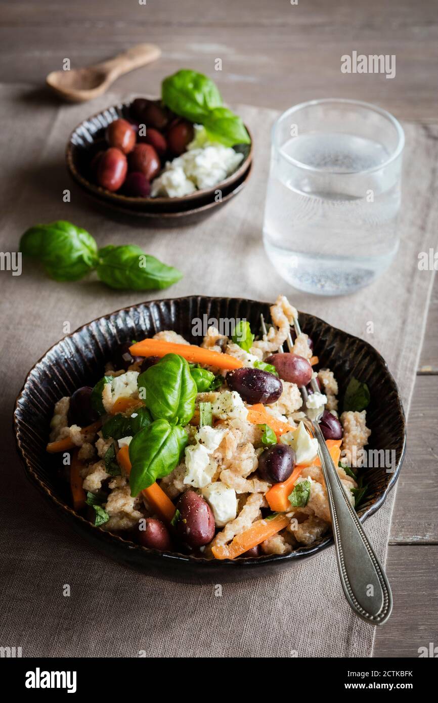 Bol de spaetzle végétarien avec carottes, olives, feta et basilic Banque D'Images