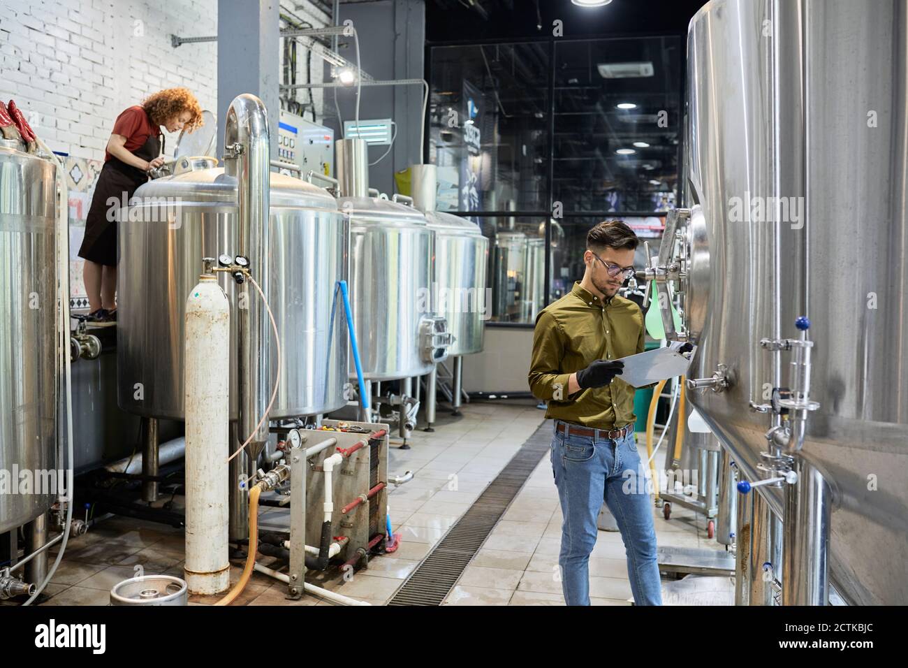 Homme et femme travaillant dans une brasserie artisanale Banque D'Images