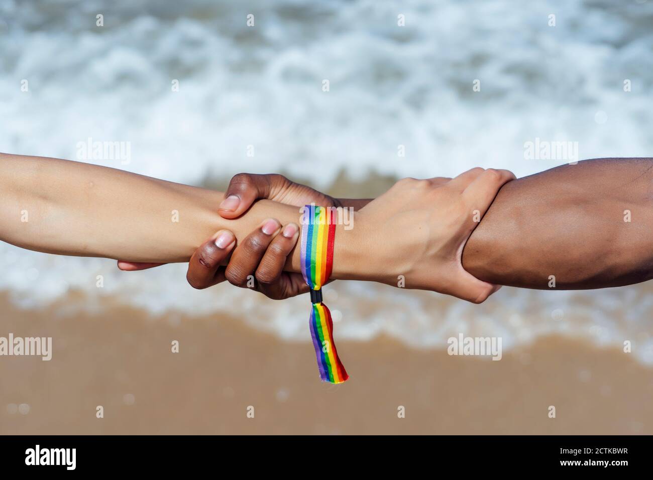 Gros plan d'un couple tenant les mains au-dessus de la mer par beau temps Banque D'Images