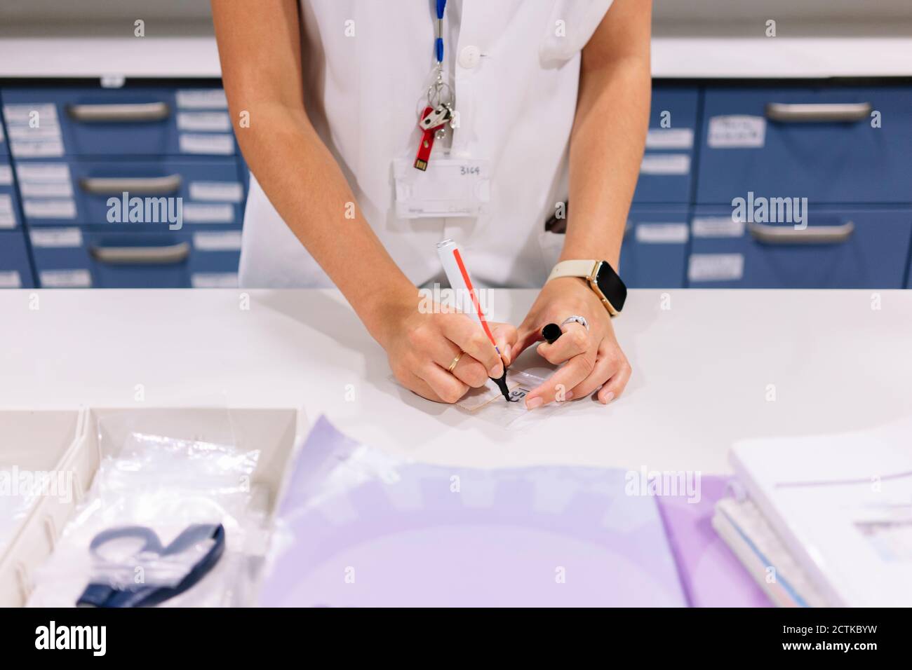 Gros plan de la pharmacienne écrivant sur le plastique au-dessus de la table salle de stockage Banque D'Images
