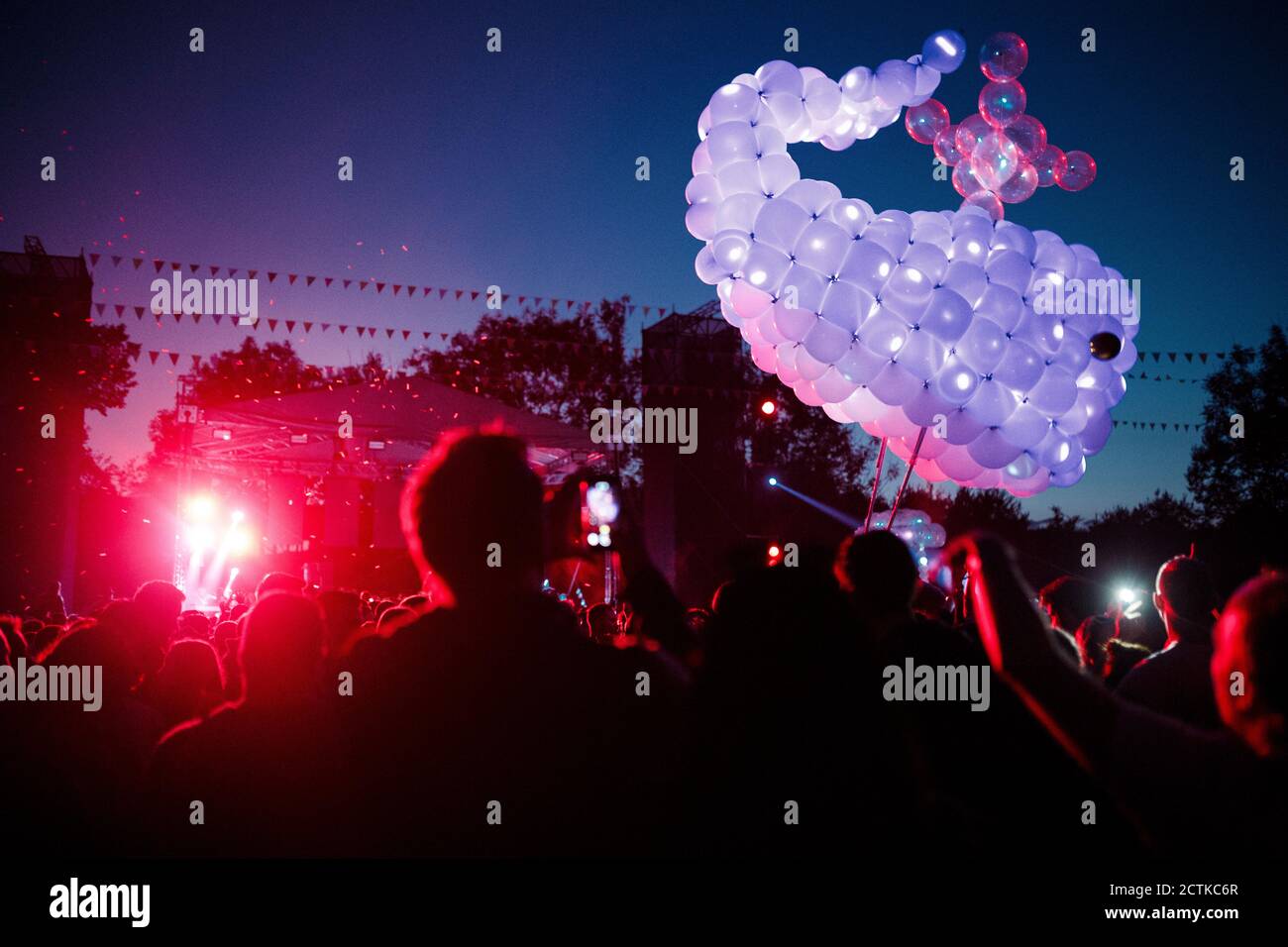 Baleine faite de ballons violets flottant au-dessus de la foule de gens s'amuser pendant le festival de musique de nuit Banque D'Images