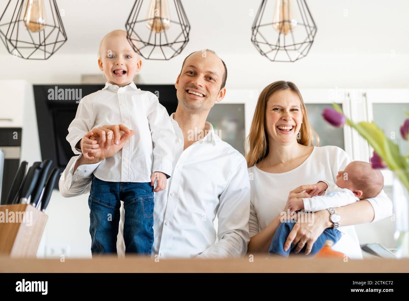 Les parents sourient tout en tenant leurs bébés garçons à la maison Banque D'Images