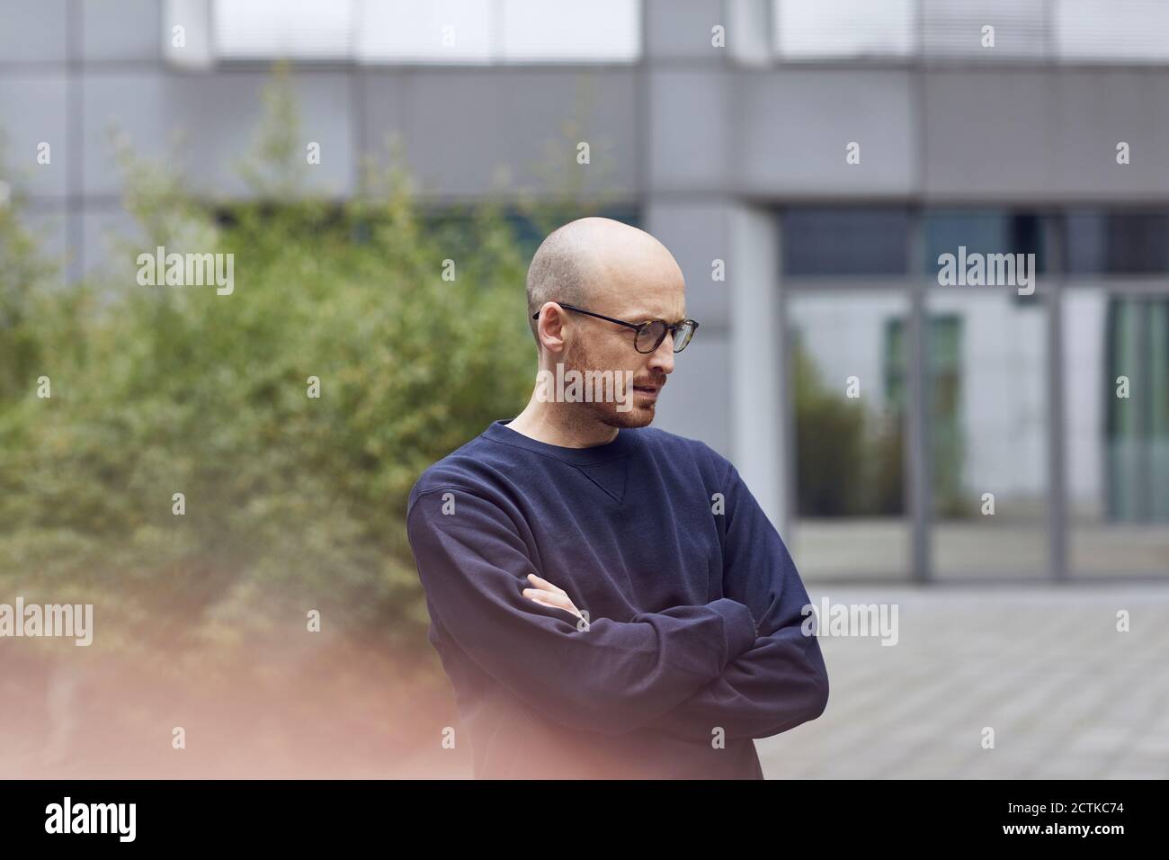 Homme attentionné regardant vers le bas avec les bras croisés sur la piste de marche Banque D'Images