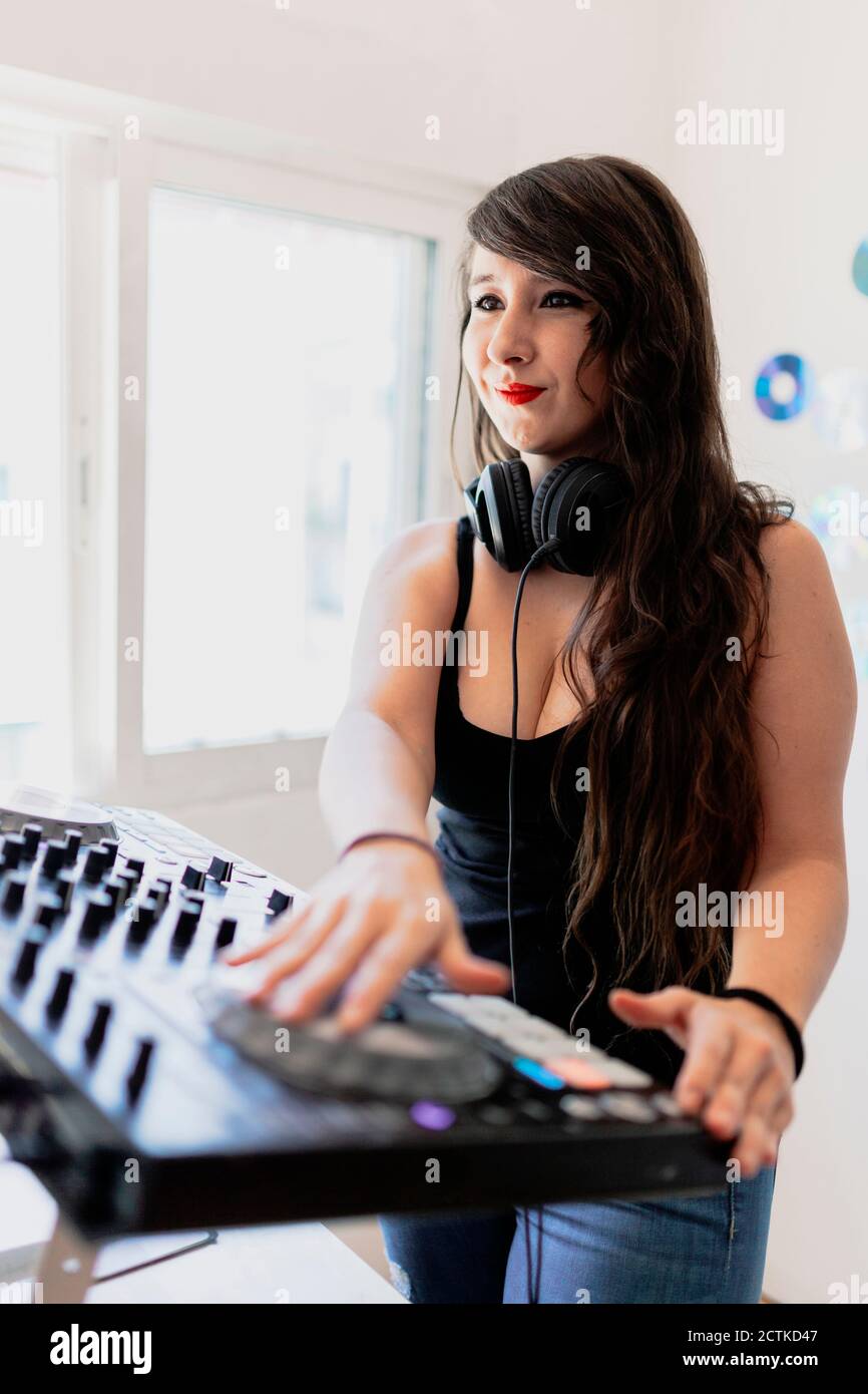 Le sourire magnifique DJ de club féminin utilisant l'équipement audio dans le studio Banque D'Images