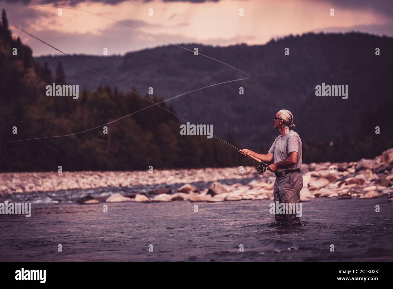 Faites voler le pêcheur avec la canne à pêche tout en vous tenant dans la rivière Banque D'Images