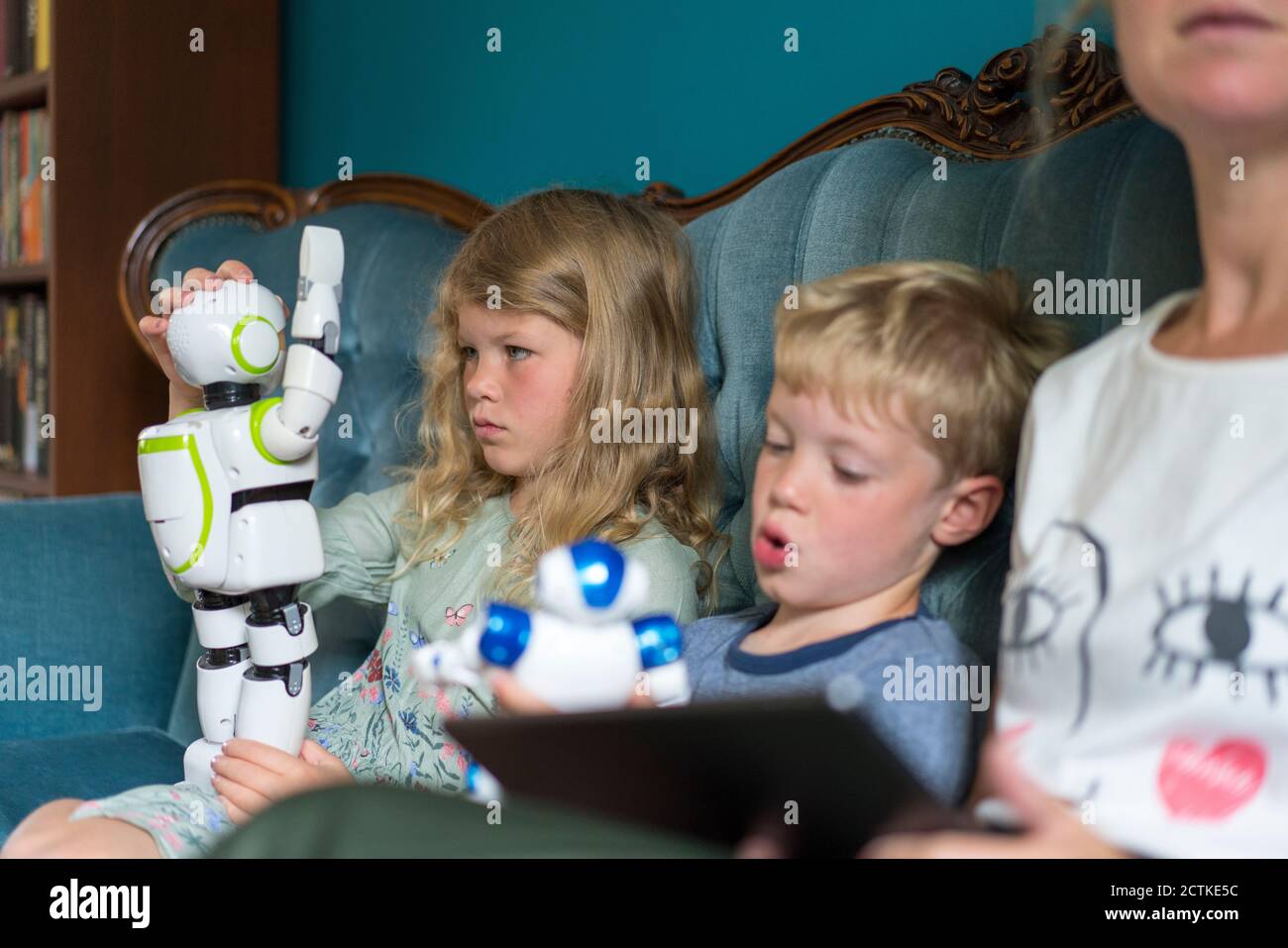 Blonde fille jouant avec le robot tout en étant assis par les frères et sœurs mère à la maison Banque D'Images
