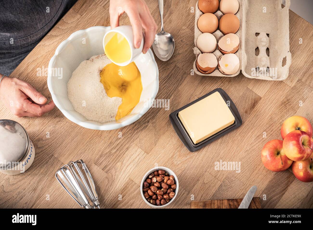 Femme à la main mettant le jaune d'œuf dans un bol tout en se tenant à îlot de cuisine Banque D'Images