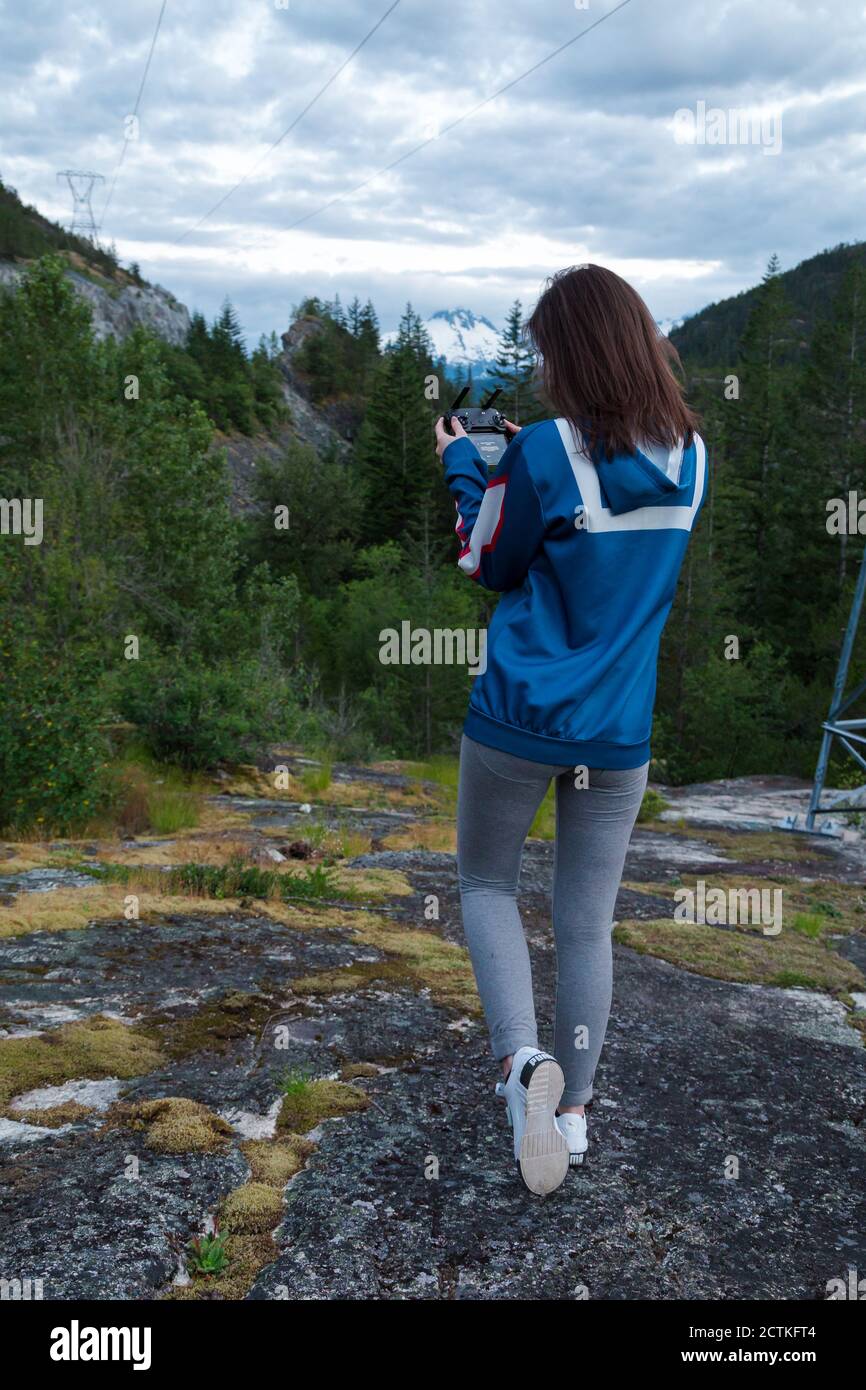 Jeune femme brune attrayante avec une radiocommande pour un drone dans la forêt. Banque D'Images