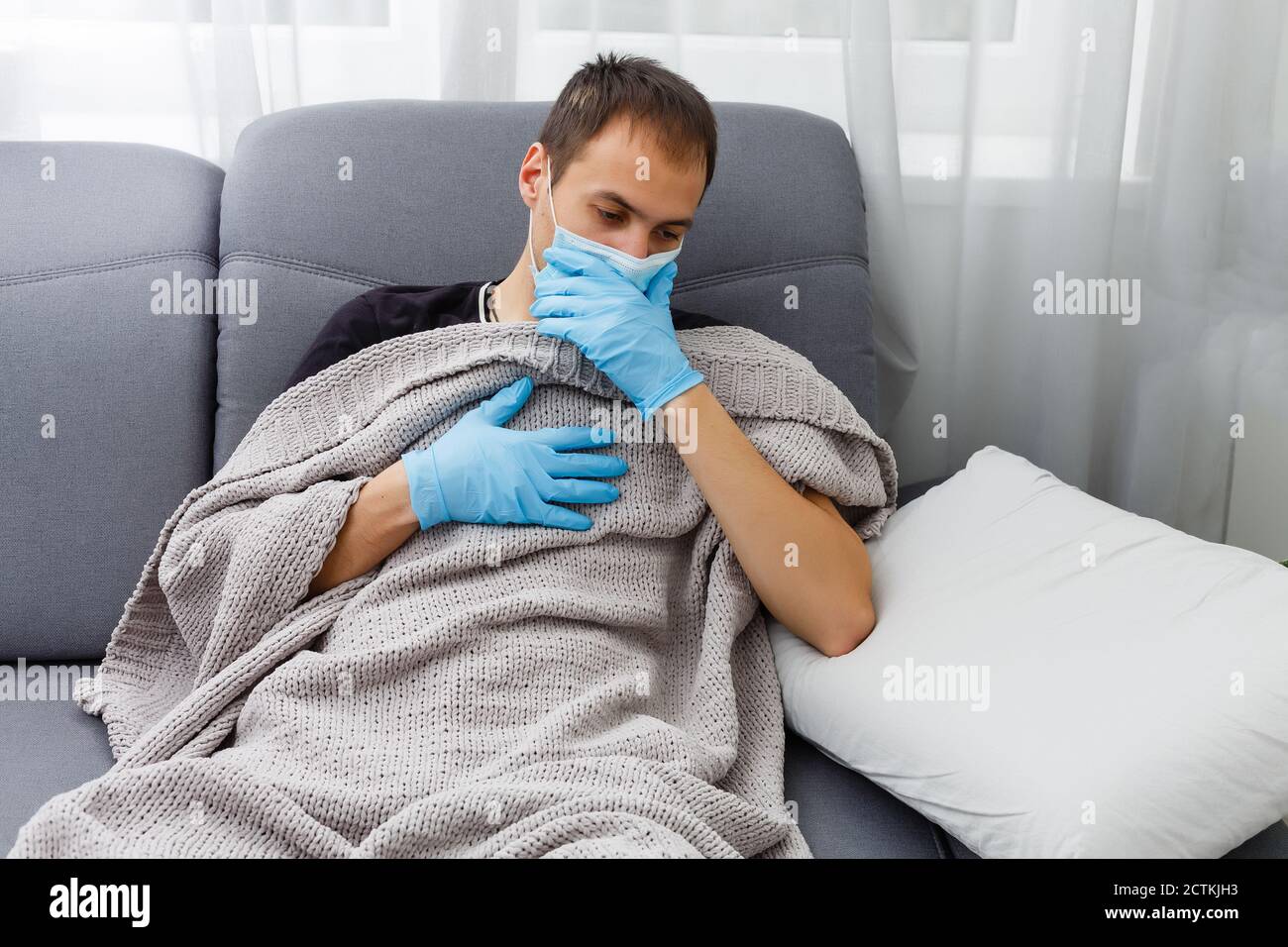 Mains avec gants bleus portant un masque médical pour protéger les voies respiratoires supérieures. La main de l'homme met sur un masque facial de protection contre le virus Banque D'Images