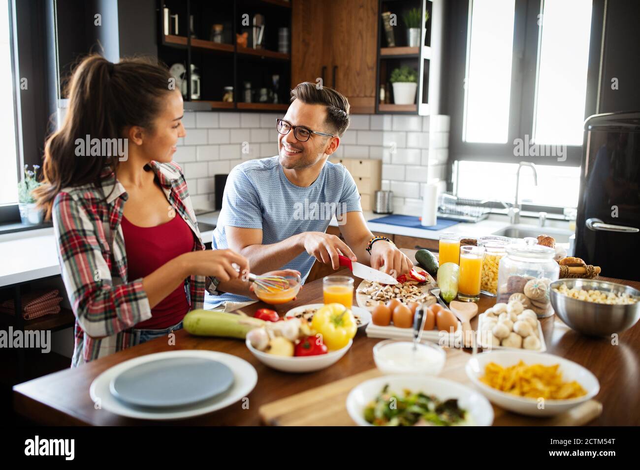 Un jeune couple heureux s'amuse dans une cuisine moderne tout en se préparant produits frais Banque D'Images