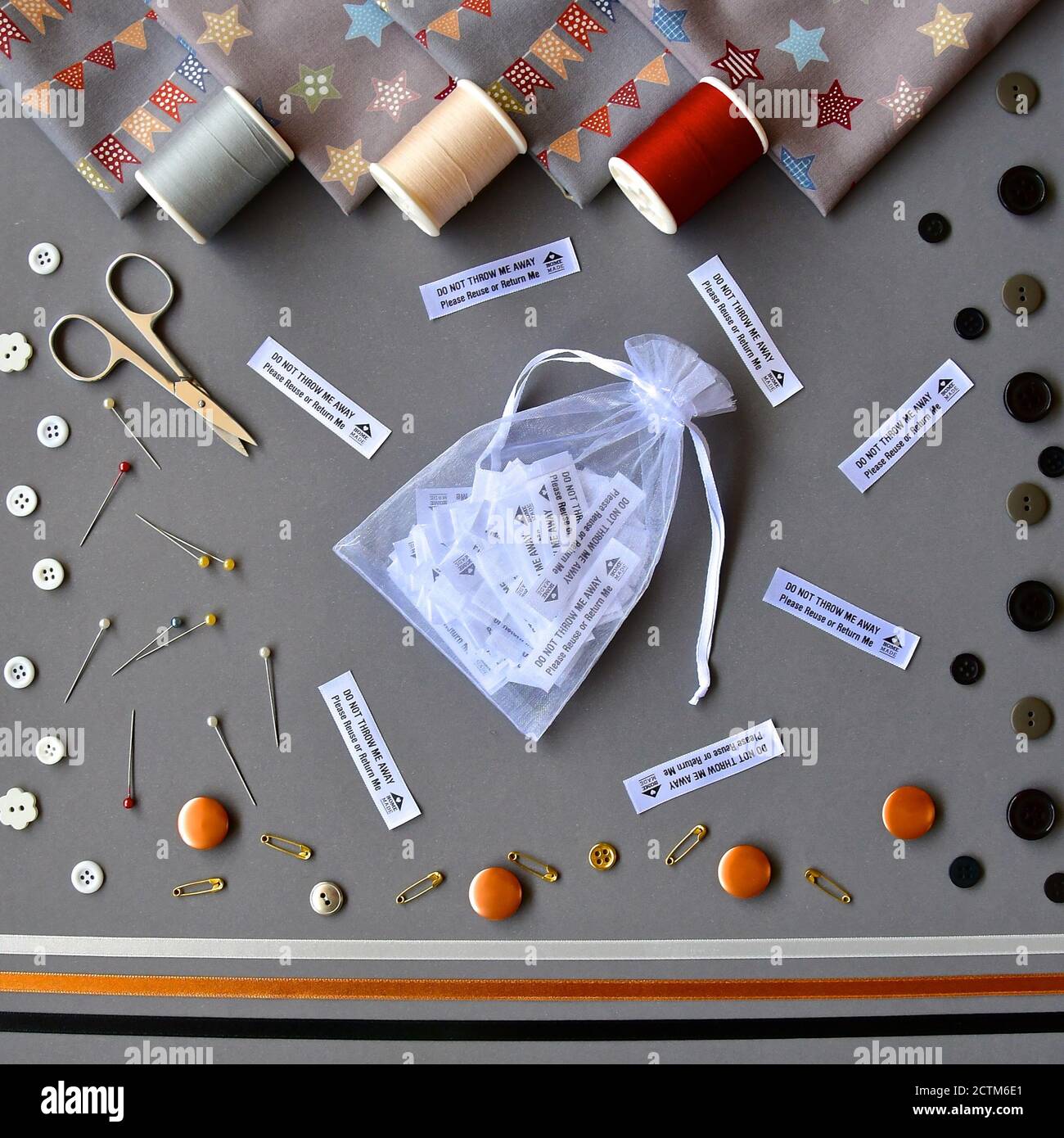 Une planéité oeil d'oiseaux d'accessoires de couture avec coton, matériel, ciseaux, épingles de sécurité, rubans, étiquettes et boutons sur fond gris. Banque D'Images