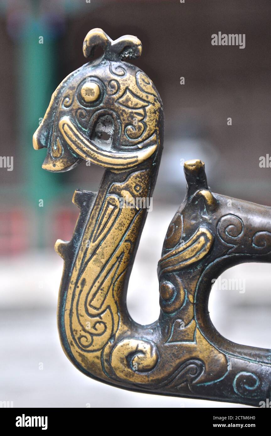 Profil latéral d'une poignée en laiton ornée sous la forme d'une créature mythique de type dragon trouvée sur une grande urne traditionnelle chinoise. Banque D'Images