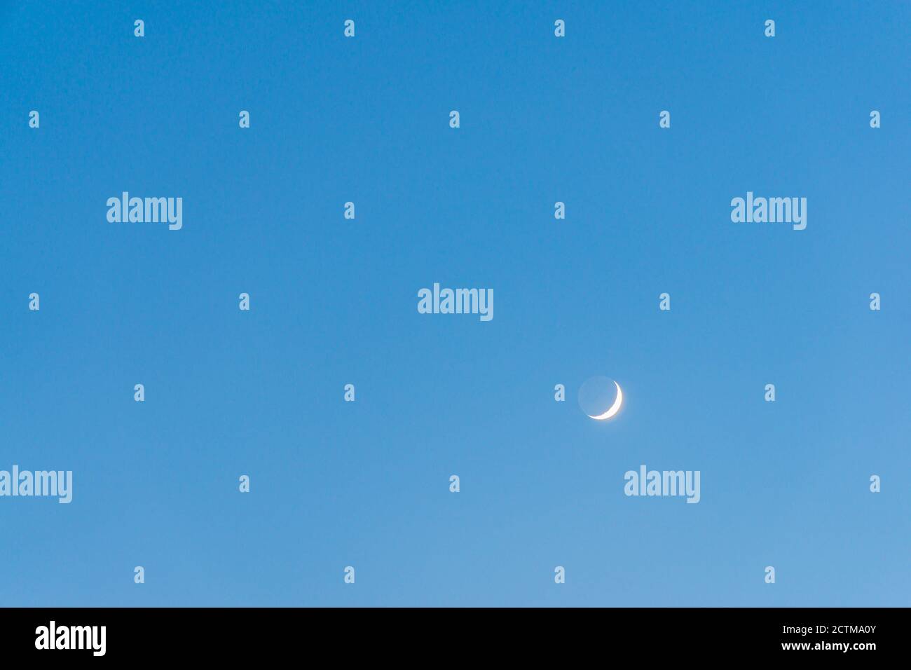 Crescent Moon et Earthshine dans le ciel bleu Banque D'Images