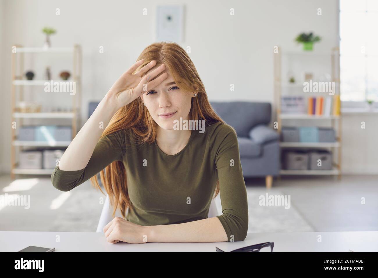 Femme fatiguée stressée regardant la caméra pendant la leçon en ligne ou rencontre et expression de maux de tête Banque D'Images