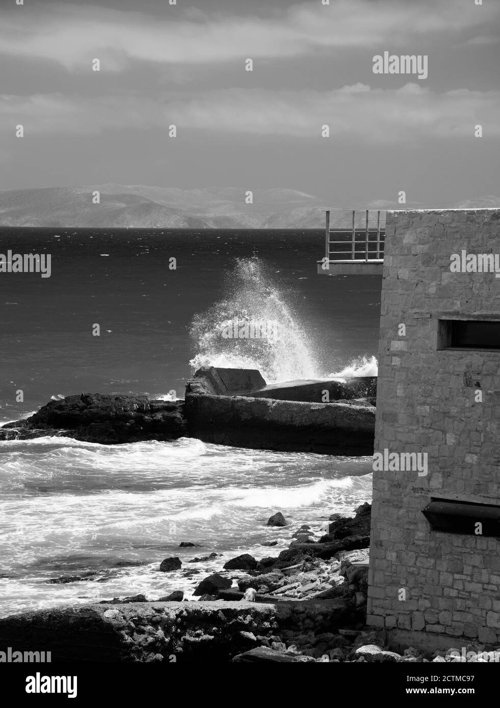 Une vague s'écrasant sur les rochers par une journée venteuse. Héraklion, Crète, Grèce. L'île de Dia (NTIA) visible en arrière-plan. Banque D'Images