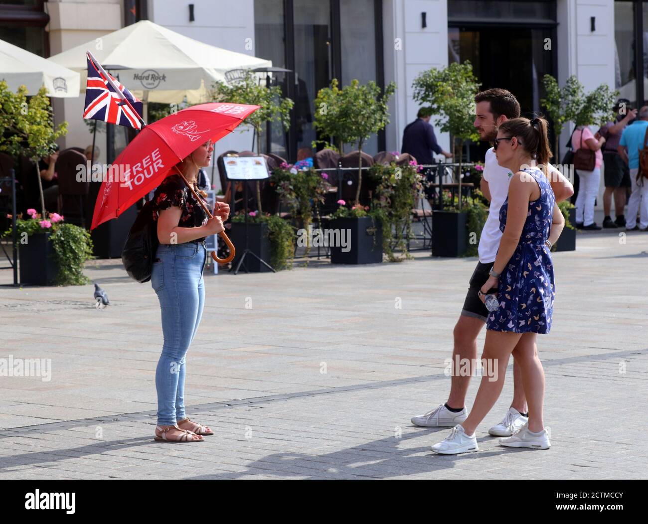 Cracovie. Cracovie. Pologne. Une femme guide tenant un parapluie avec l'inscription « Free Tour » et le drapeau britannique parlant à de jeunes toristes couple dans le Banque D'Images