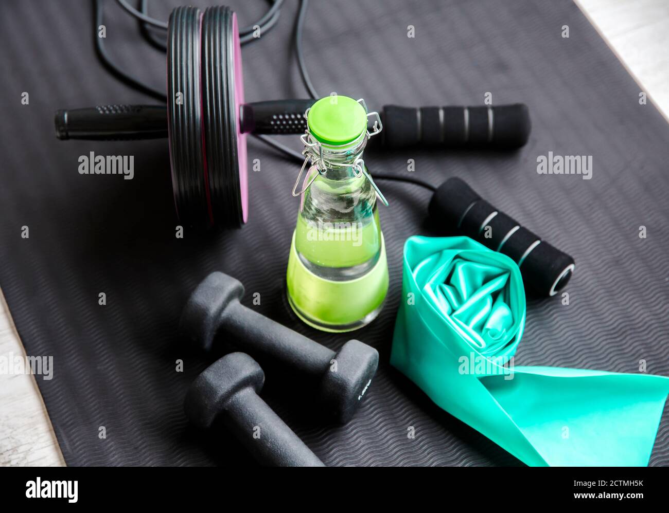 Mise au point sélective sur le bouchon de bouteille d'eau en verre. Consommation d'eau pure fraîche pendant l'entraînement concept. Bouteille sur tapis d'exercice avec d'autres équipements d'entraînement. Banque D'Images