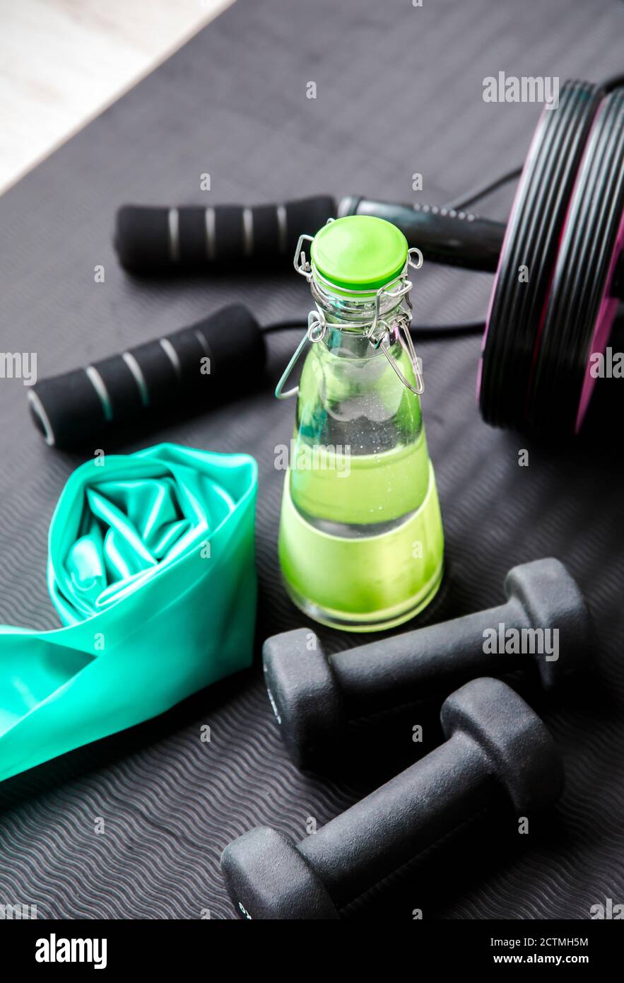 Mise au point sélective sur le bouchon de bouteille d'eau en verre. Consommation d'eau pure fraîche pendant l'entraînement concept. Bouteille sur tapis d'exercice avec d'autres équipements d'entraînement. Banque D'Images