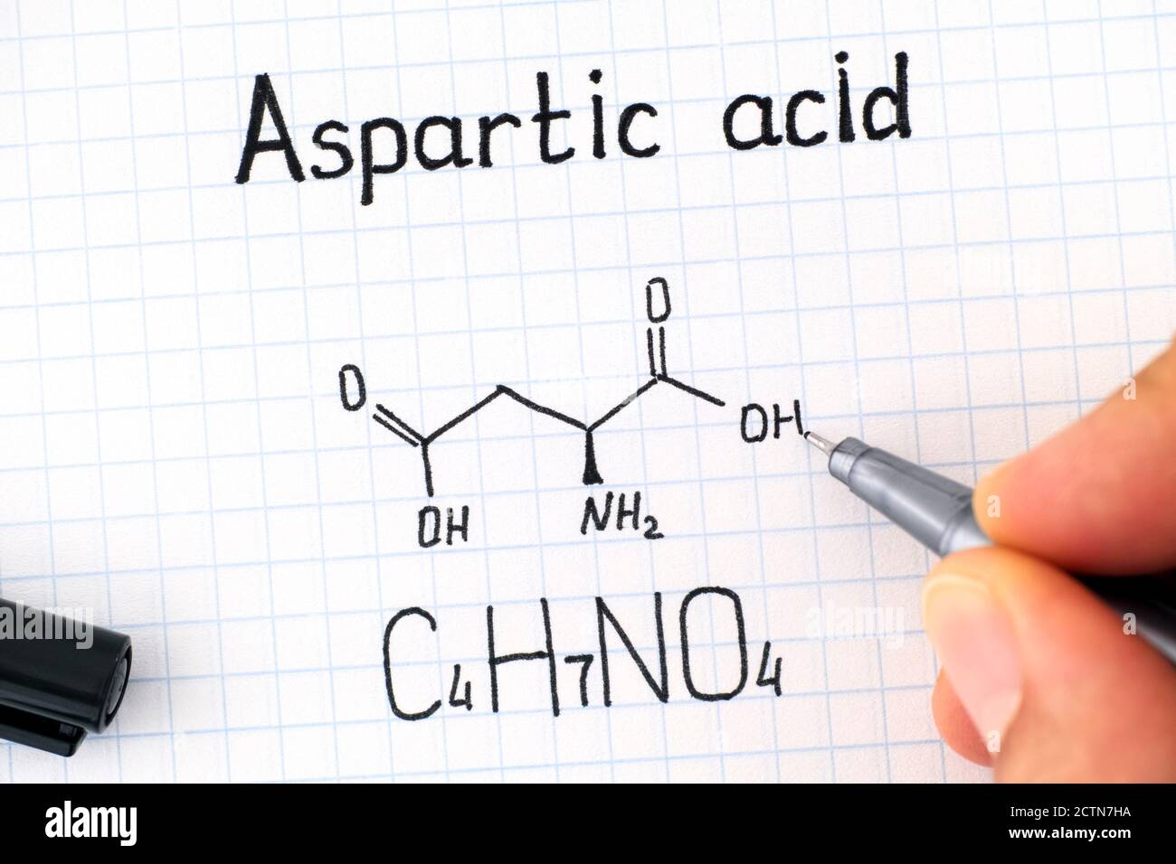 Femme doigts avec écriture stylo Formule chimique de l'acide aspartique. Gros plan. Banque D'Images