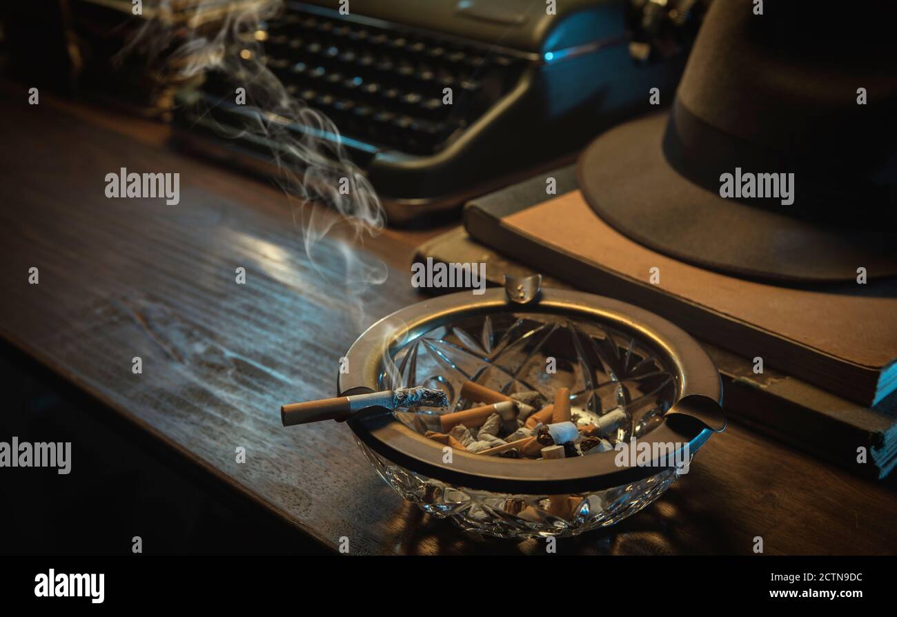 Ordinateur de bureau de détective vintage avec machine à écrire, chapeau fedora et cendrier, style de noir de film Banque D'Images