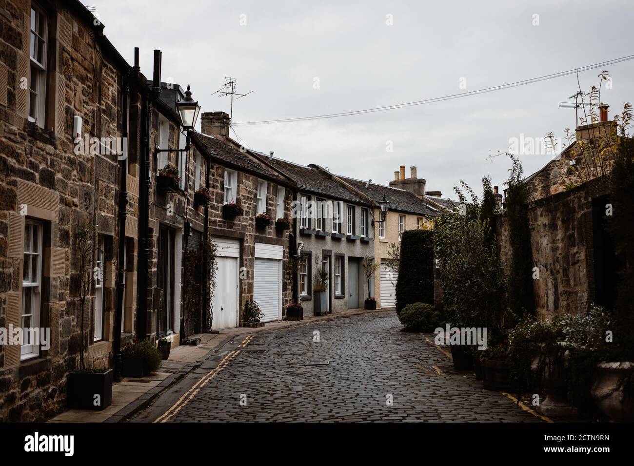 Vue en perspective de la vieille rue étroite avec des immeubles résidentiels de grunge Sur fond de ciel gris dans les Highlands écossais Banque D'Images
