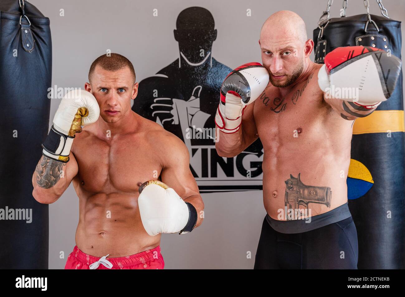 Des sportifs déterminés en gants de boxe debout en position de combat dans faire de la gym pendant l'entraînement et regarder l'appareil photo Banque D'Images